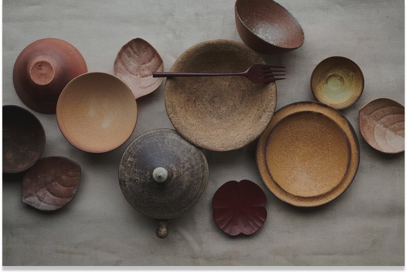 Flat-lay of handmade ceramic plates, bowls and lids